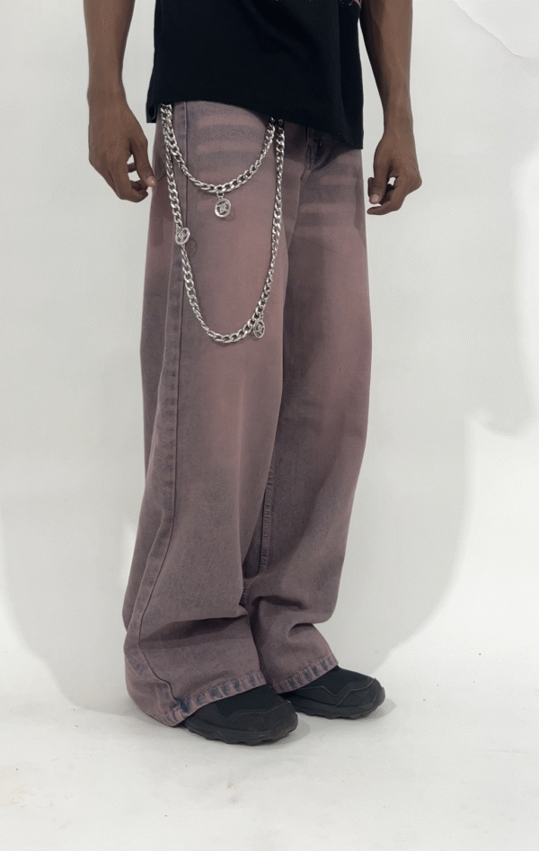 Wide-leg dust rose pants with a relaxed fit and vintage-washed finish, styled with a black graphic t-shirt and chunky sneakers.