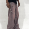 Wide-leg dust rose pants with a relaxed fit and vintage-washed finish, styled with a black graphic t-shirt and chunky sneakers.